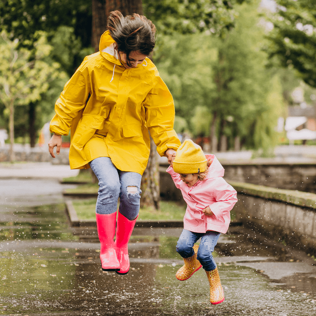  Mamma og datter hopper i vanndammer – lek og moro når det regner.