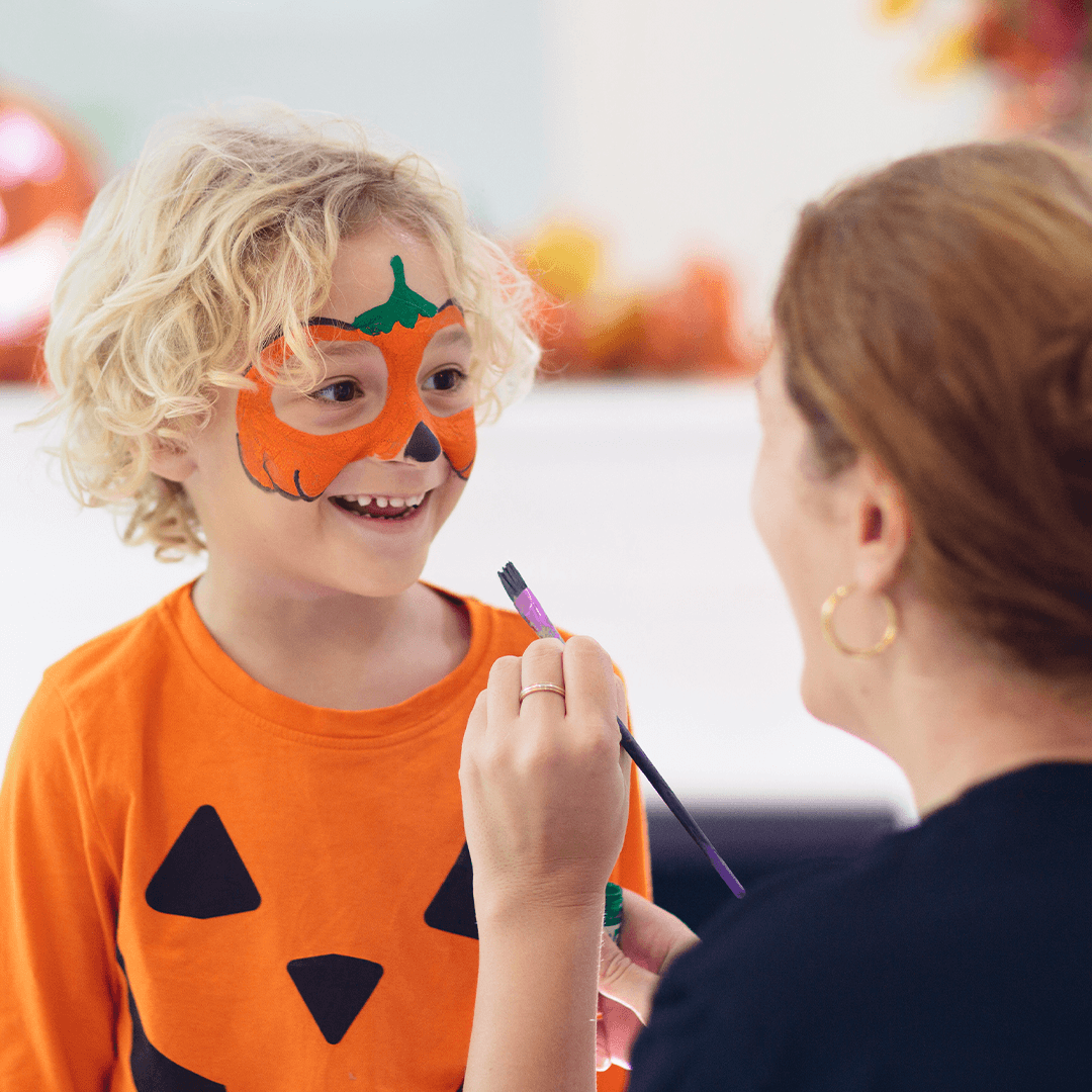 Mor maler et gresskarmønster i ansiktet på sønnen til halloween