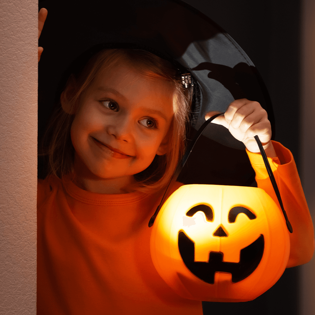 Jente holder en gresskarlykt under halloween