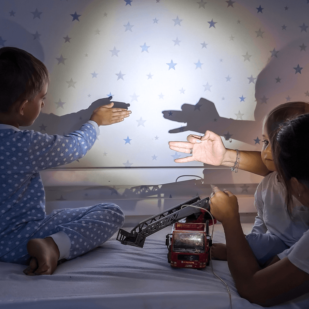 Mother and children creating shadow shapes on the wall with a flashlight.
